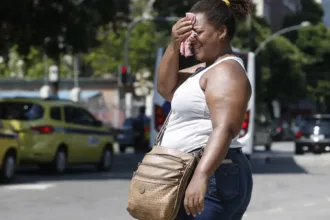 Mulher limpando o suor rosto com um pano por causa do calorão no Rio de Janeiro