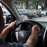 Motorista dirige por avenida olhando aplicativo de corrida. Foto: Rovena Rosa/Agência Brasil