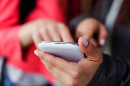 two-beautiful-students-using-mobile-phone-street_rede_social